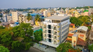 A multi-story building with a flat roof, surrounded by greenery and other buildings.