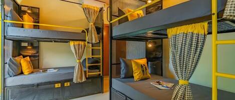 A bunk bed room with three levels, each with a mattress and pillows, and curtains tied at the head.