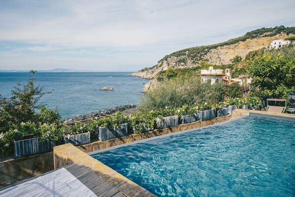 En swimmingpool med utsikt över havet och en sluttning med byggnader.