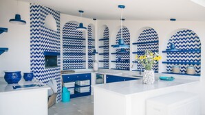 A modern kitchen with blue and white zigzag patterned walls, a central island, and blue pendant lighting. - Villa Heart with private pool - My Rental Homes (Massa Lubrense)