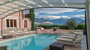 Zona de piscina con sillas de descanso y vistas a montañas.