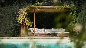 A poolside area with a covered seating area and a planter.