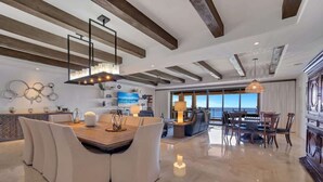A spacious living area with a dining table, chairs, and a large window offering a view.