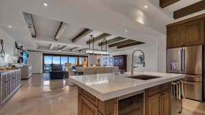 A spacious kitchen with a large island, wooden cabinets, and a stainless steel refrigerator.