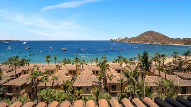 A coastal hotel with multiple buildings, a beach, and boats in the water.