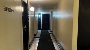 A hotel hallway with a black carpet, white tiled floors, and doors marked "Elevator". - Hotel Sogo EDSA Shaw Blvd (Mandaluyong)