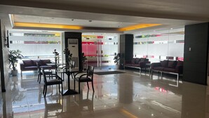 A modern lobby with a reception desk, seating area, and a glass partition. - Hotel Sogo EDSA Shaw Blvd (Mandaluyong)