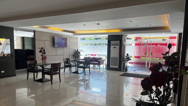 A modern hotel lobby with a reception desk, seating area, and a large TV screen. - Hotel Sogo EDSA Shaw Blvd (Mandaluyong)