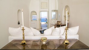 Une pièce avec un canapé blanc, deux chandeliers et une table sur laquelle se trouve un saladier.