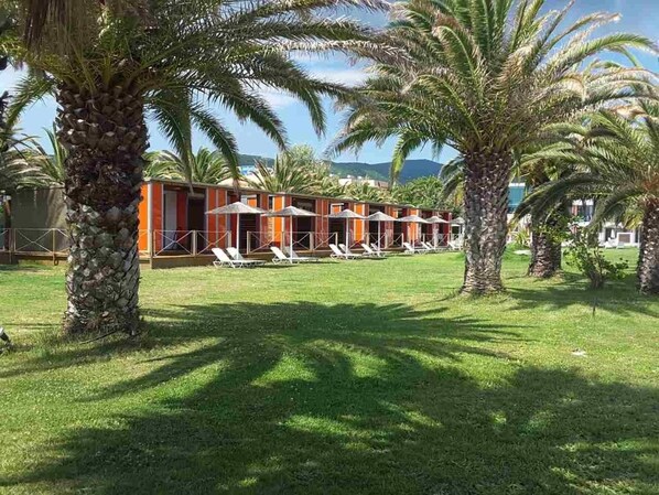 A resort with palm trees, a pool area, and a building with orange and white walls.