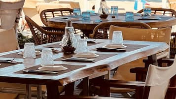 Un comedor con mesas y sillas de madera, cristalería transparente y una botella decorativa.