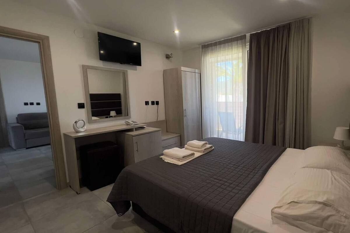 Ein Hotelzimmer mit Bett, Schreibtisch, Spiegel, Fernseher und Kleiderschrank.