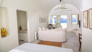 A spacious bedroom with a large bed, a view of the sea, and a modern chandelier. - My Rental Homes - Aloy Suite with outdoor hot tub, covered Jacuzzi and sea view (Fira)