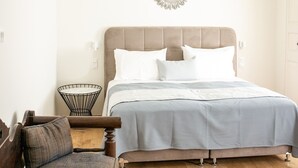 A bedroom with a bed, a round mirror, a small round table, and a chair. - My Rental Homes - Palea Suite with Jacuzzi, sea view e wonderful rooftop terrace (Fira)