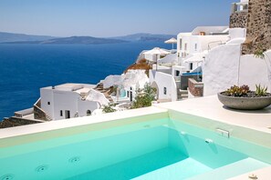 A pool with a clear view of the sea and white buildings in the background.