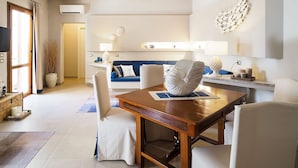 Un soggiorno moderno con un tavolo da pranzo in legno, sedie bianche, un divano blu e un elemento decorativo a parete.