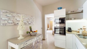 Una cucina moderna con mobili bianchi, elettrodomestici in acciaio inossidabile e un tavolo da pranzo in vetro trasparente.