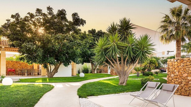 A well-maintained outdoor area with a pathway, lounge chairs, and various trees. - Sun Stone with garden and pool - My Rental Homes (Trapani)