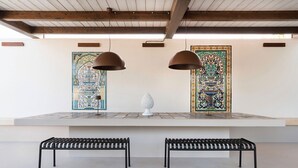 Um interior moderno com dois bancos de metal preto, um pedestal branco e duas luminárias pendentes.