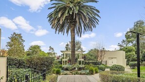 Un jardin bien entretenu, agrémenté d’un grand palmier, d’un belvédère et d’un bâtiment doté d’un toit plat.