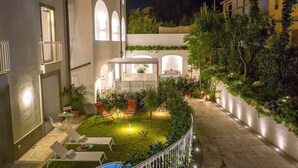 A courtyard with a pool, lounge chairs, and a pergola.