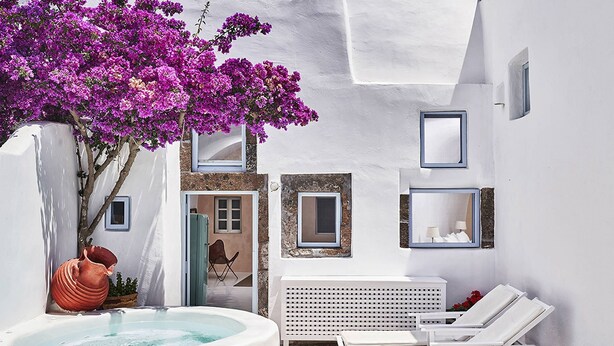 A spa area with a hot tub, white lounge chairs, and a large purple flowering tree.