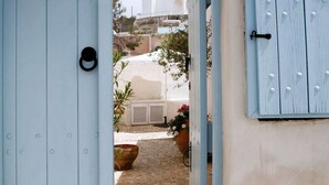 A doorway leading to a cobblestone courtyard with potted plants and a palm tree in the background.