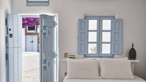 A bedroom with a bed, a window with blue shutters, and a view of a pool and garden.