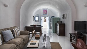 A spacious living room with a high arched ceiling, a sofa, a coffee table, and a television.