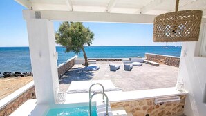 A covered outdoor area with a pool, lounge chairs, and a view of the sea. - Maison Ranya - My Rental Homes (Exomytis)