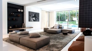 A modern living room with a sectional sofa, a coffee table, and a black shelving unit with decorative items. - My Rental Homes - Villa Sound luxury property with pool and privacy (San Jose)