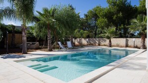 A rectangular swimming pool with clear blue water, surrounded by a tiled deck and palm trees. - My Rental Homes - Villa Salentina with private pool and large private garden (Cutrofiano)