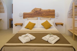 A bedroom with a wooden headboard, two bedside tables, a bed with white and mustard pillows, and two towels on the bed. - My Rental Homes - Villa Salentina with private pool and large private garden (Cutrofiano)