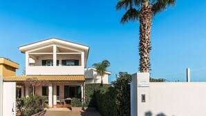 Una casa de dos pisos con un balcón, una palmera y un letrero que dice 'KALIKA n.3'.