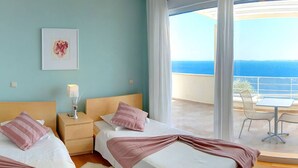 Een hotelkamer met twee bedden, een nachtkastje, een ingelijste foto en een balkon met een tafel en stoelen.