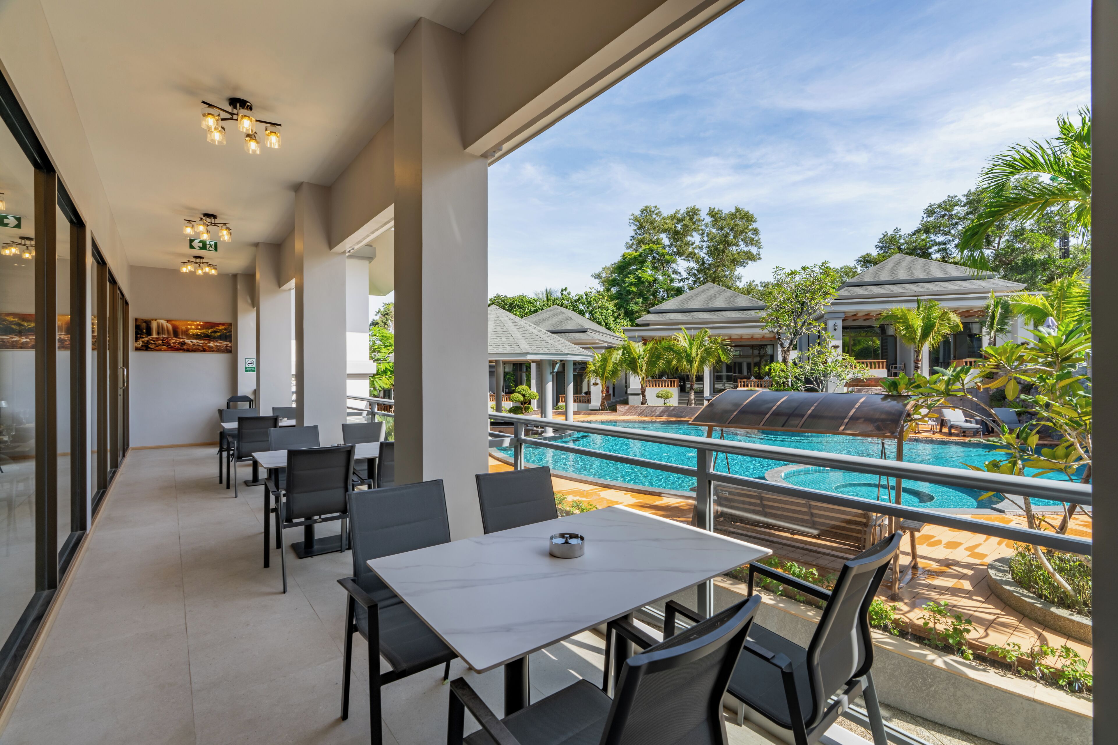 Un balcón con vista a la piscina, mobiliario exterior y zona de comedor.