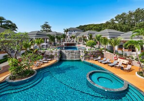 Un complejo turístico con piscina central, zonas de descanso y varias villas.