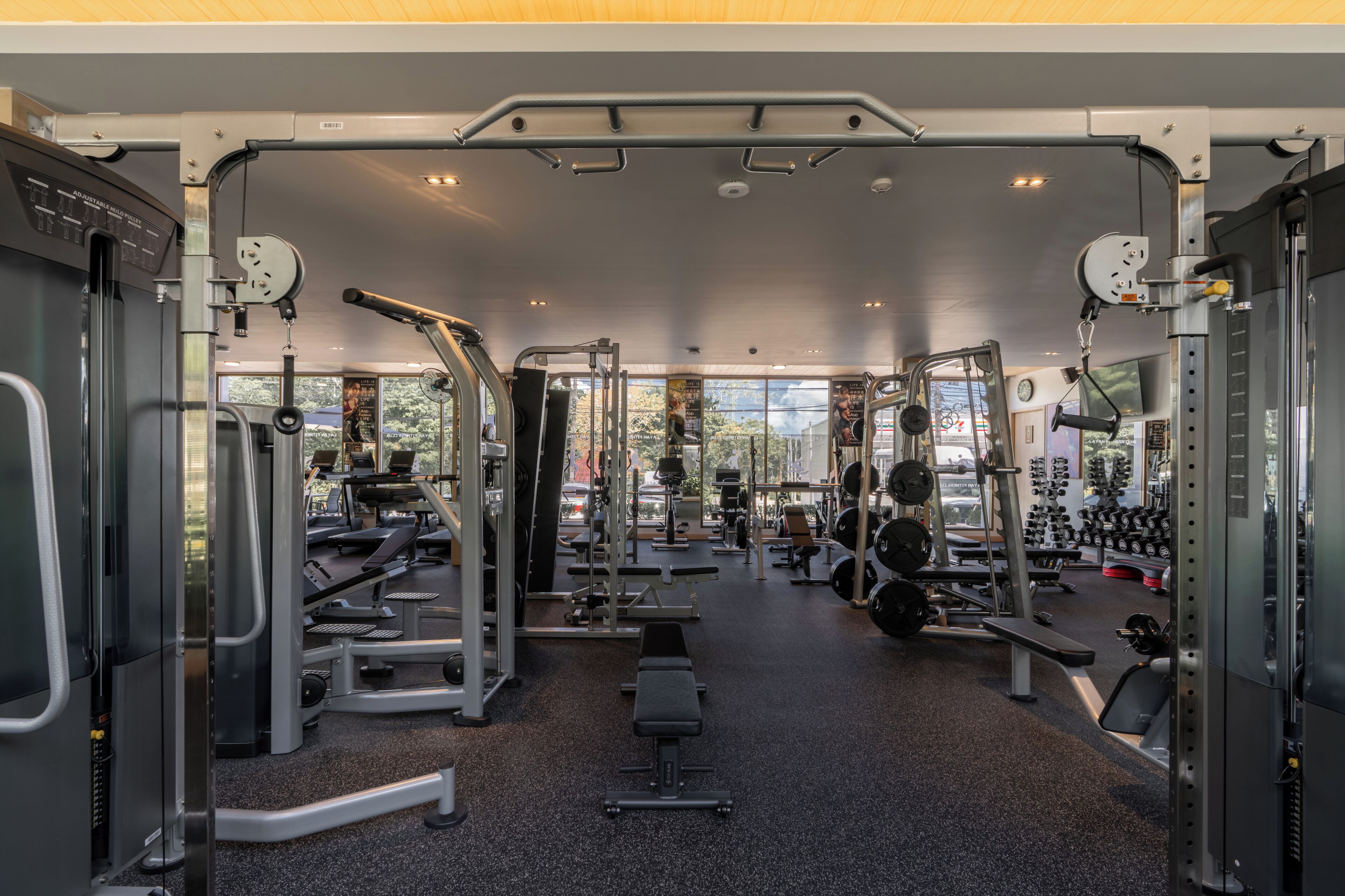 Une salle de sport équipée de divers appareils d’exercice, de bancs et d’espaces dédiés à la musculation.