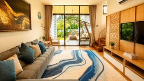 A modern living room with a sofa, a TV, and a large window with a view of greenery. - A.Z. Sunrise Resort & Fitness Club (Choeng Thale)