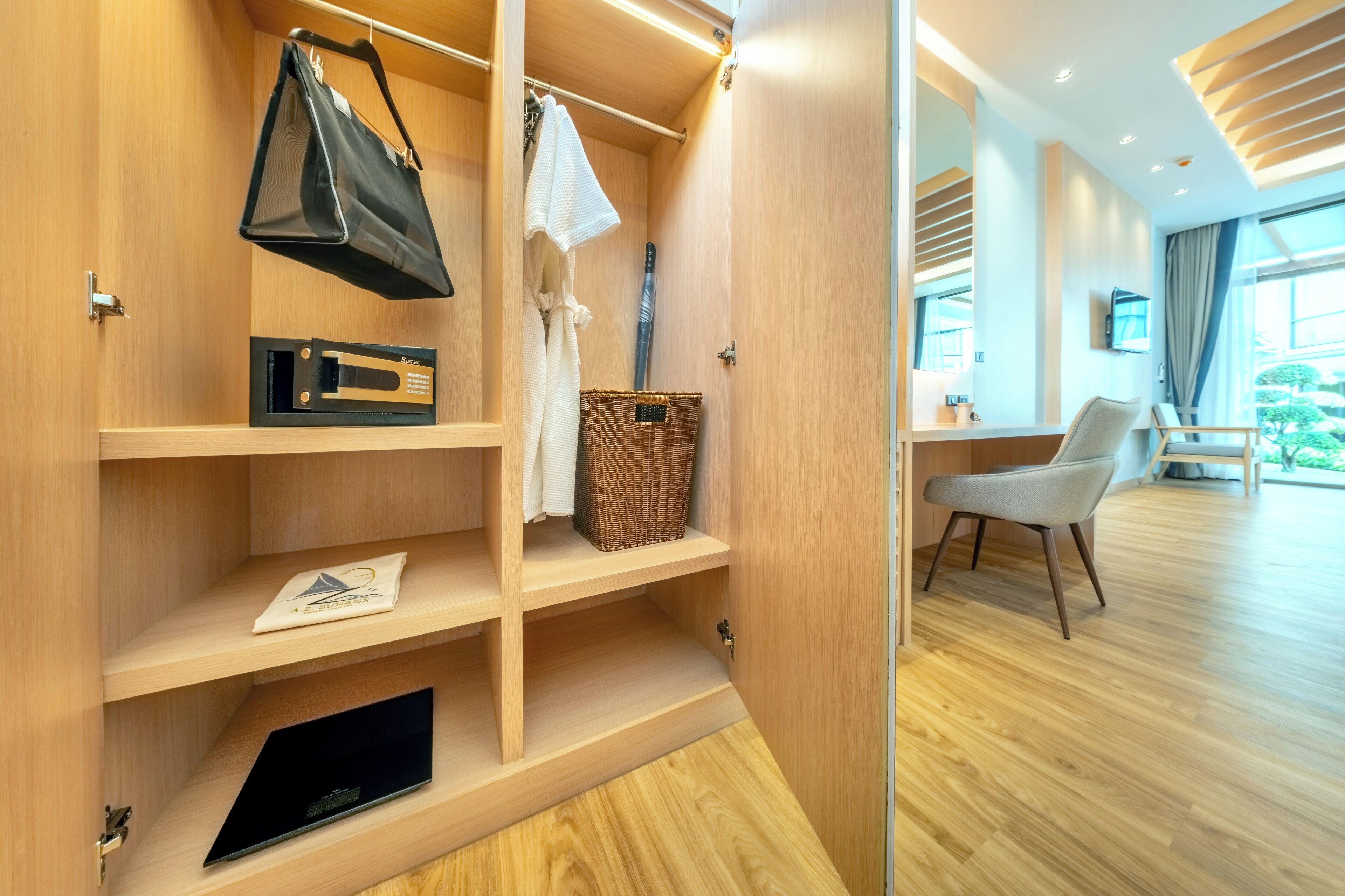 Een moderne hotelkamer met houten planken, een laptop, een zwarte tas en een rieten mand.