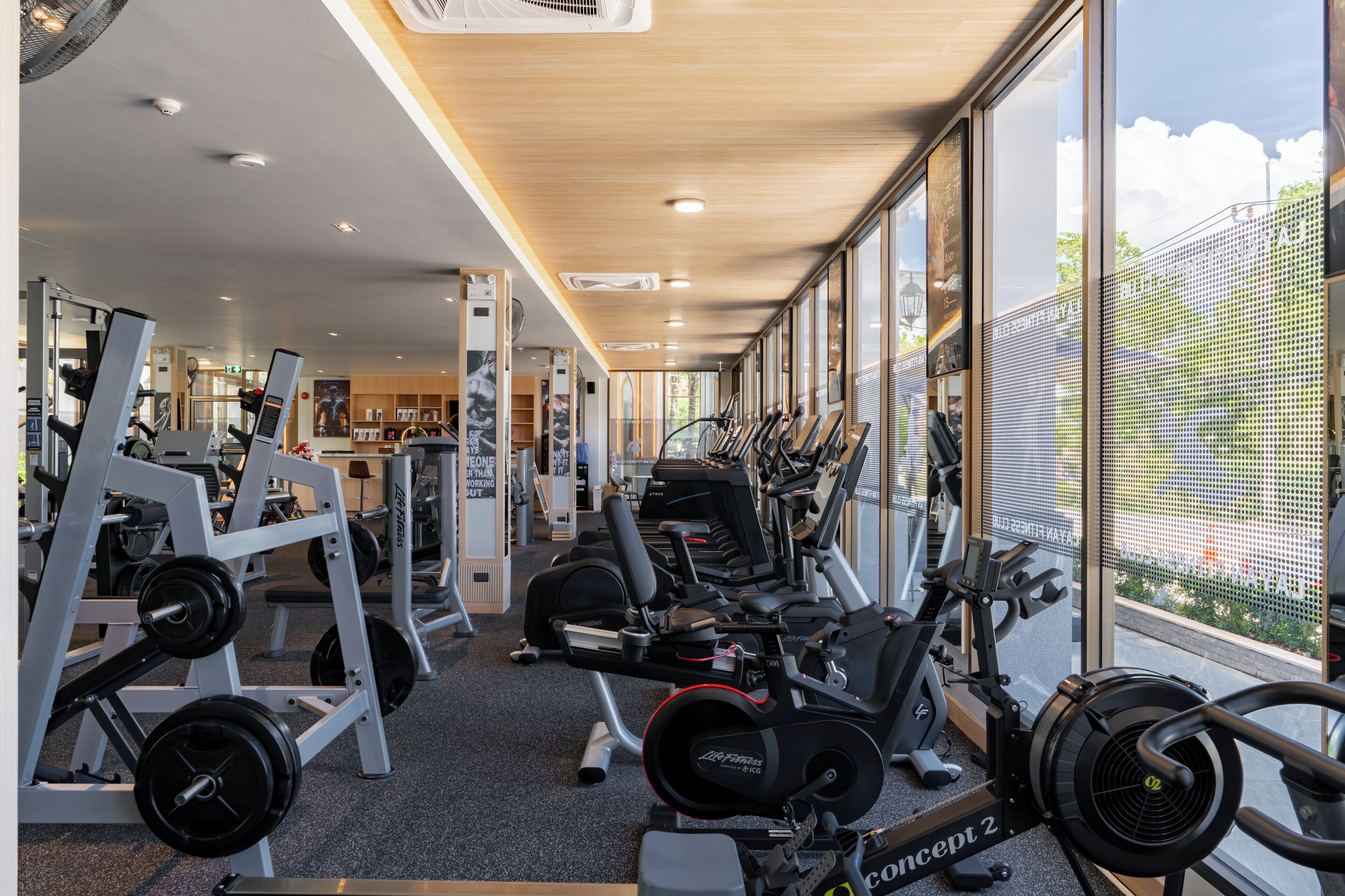 Une salle de sport équipée de machines de cardio, d’appareils de musculation et dotée d’une grande fenêtre donnant sur l’extérieur.