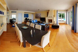 A spacious living area with a dining table, sofas, and a fireplace. - Villa Azzurra with private pool - My Rental Homes (Corfu)