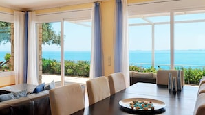 Un espace repas comprenant une table, des chaises et une vue sur la mer.