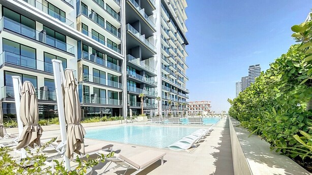 Um hotel moderno com piscina, espreguiçadeiras e um jardim bem cuidado.