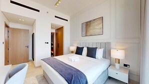 Quarto de hotel moderno com uma cama grande, abajures, um guarda-roupa de madeira e um quadro na parede.