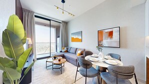 Uma sala de estar moderna com sofá, mesa de jantar e cadeiras, janelas amplas e vista para a cidade.