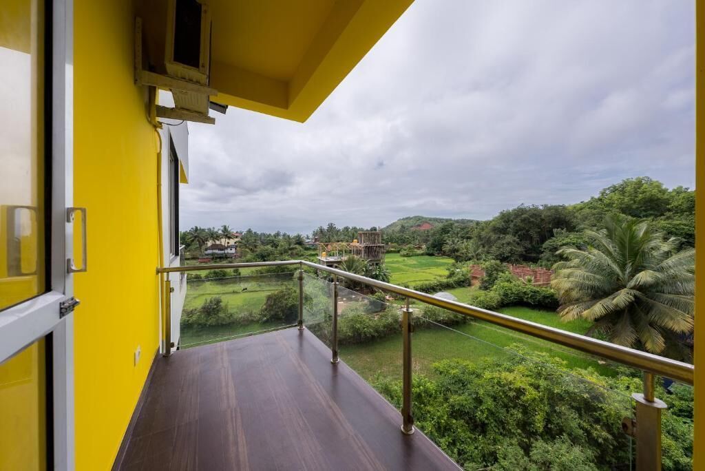 Un balcon offrant une vue sur un paysage verdoyant et luxuriant, ainsi que sur un bâtiment situé au loin.