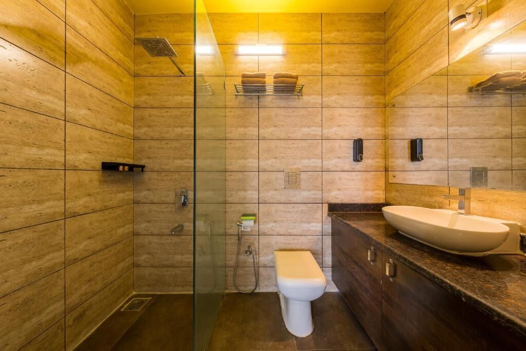 Un baño moderno con cabina de ducha de vidrio, inodoro blanco y un lavamanos amplio con encimera de mármol.