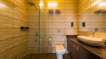 Un baño moderno con cabina de ducha de vidrio, inodoro blanco y un lavamanos amplio con encimera de mármol.