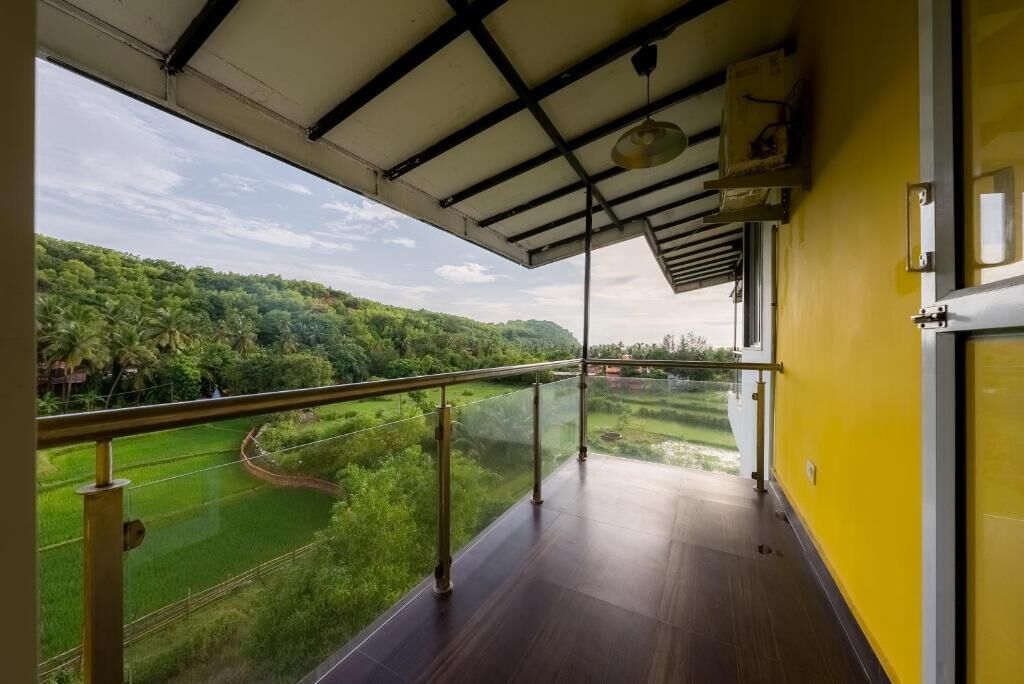 A balcony with a view of a green landscape and a clear sky.